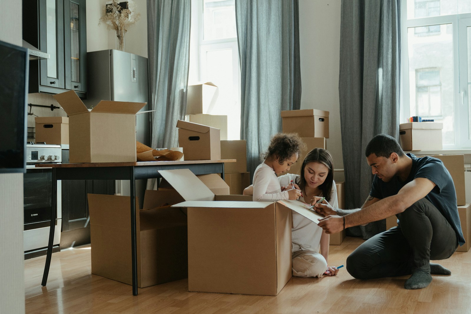 a man and a little girl are sitting on the floor in front of boxes, renters
